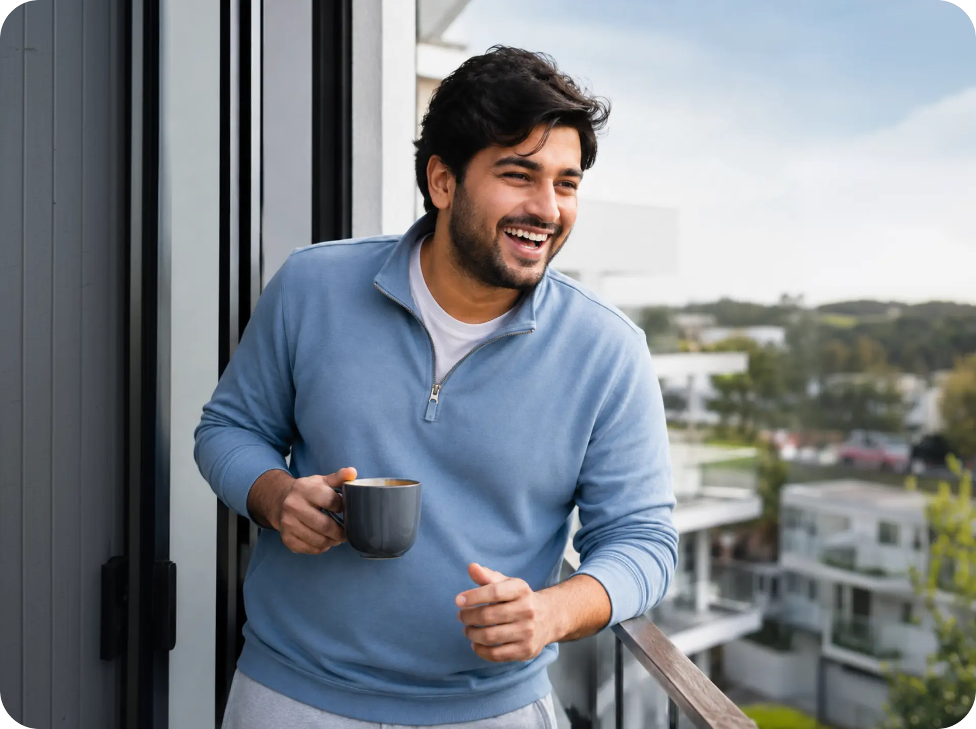 A man laughing on his balcony in the morning with a mug of coffee, breathing easily